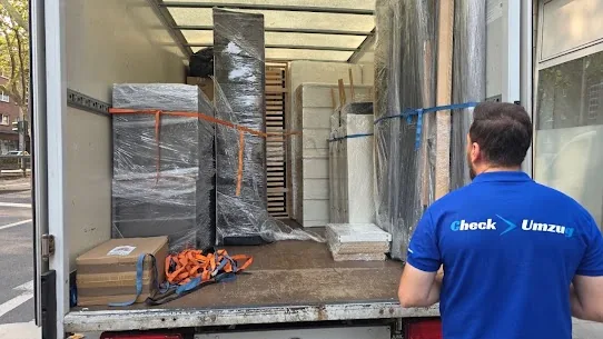Mitarbeiter von Check Umzug vor dem beladenen Umzugswagen – Möbel in Folie verpackt und mit Gurten gesichert
